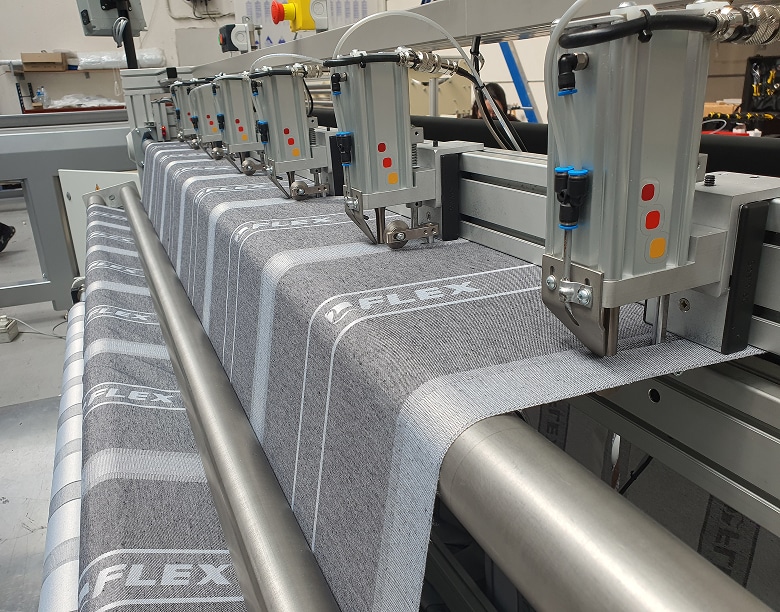 Vista en primer plano de los múltiples sonotrodos del sistema de corte por **ultrasonidos**, encargados de separar el tejido acolchado mediante vibración de alta frecuencia, logrando un acabado sin costuras ni hilos.