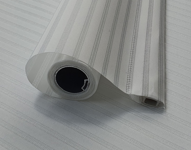 Vista en detalle del producto acabado de la máquina VU ESTOR, mostrando el dobladillo final perfectamente sellado por ultrasonidos sin costuras en el tejido de la cortina técnica.