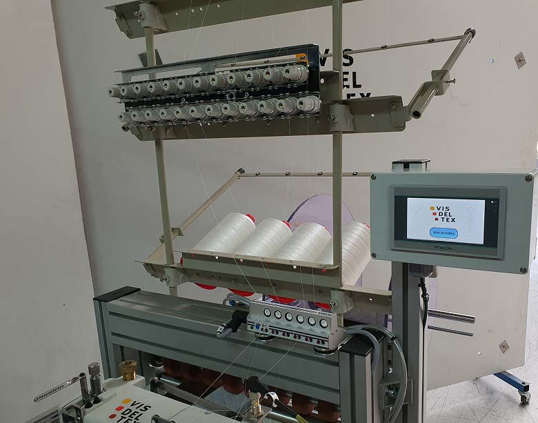 Vista del sistema de bobinas múltiples de hilo que alimenta de manera constante y sincronizada a la máquina de costura multiagujas, garantizando la continuidad de la producción.